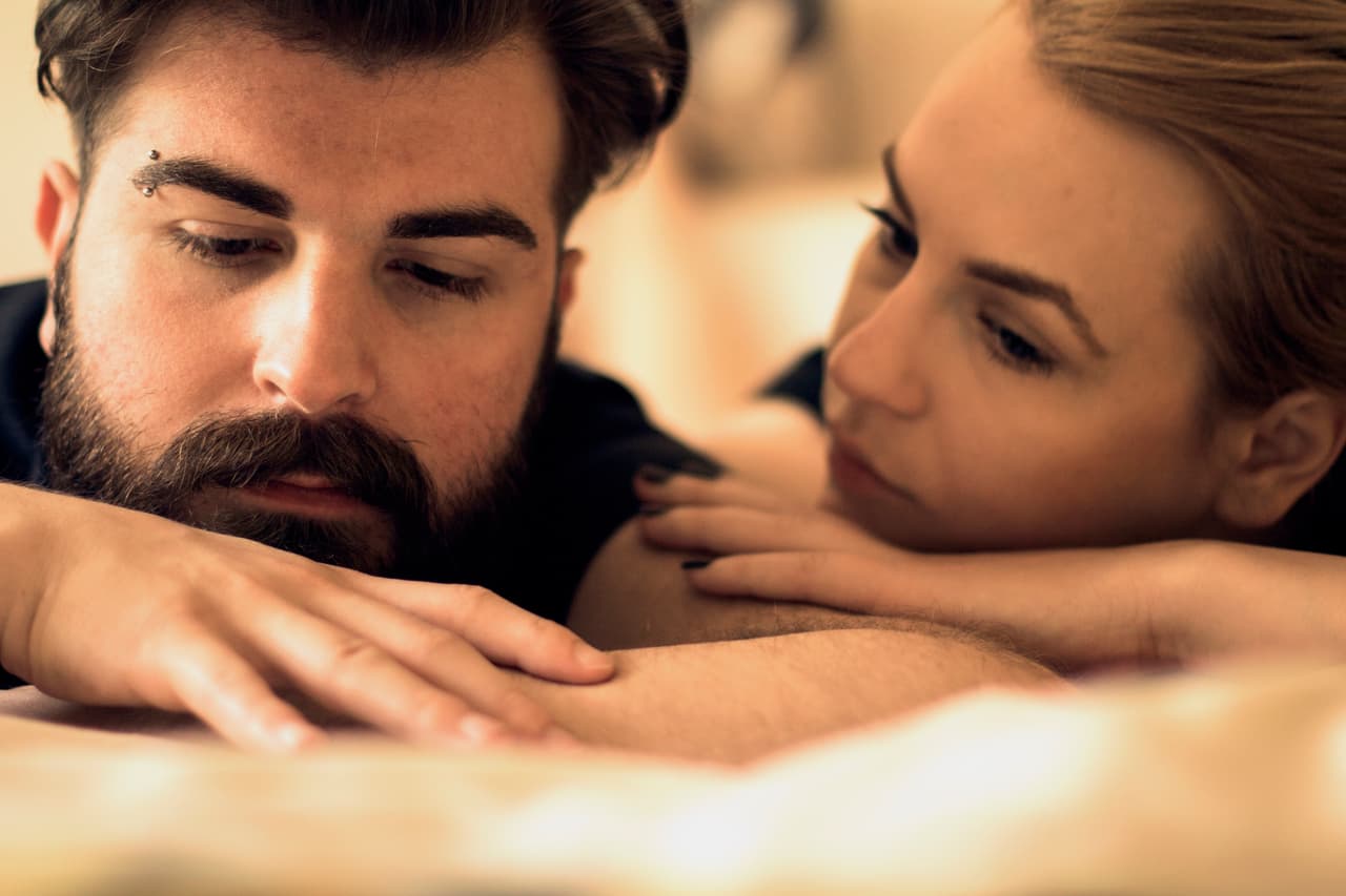 Unhappy young heterosexual couple in bedroom