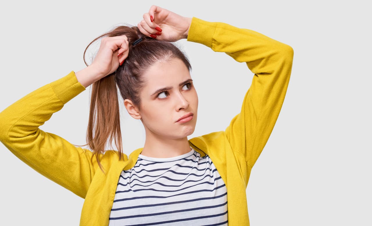 Mujer ajustando su cabello con cola de caballo