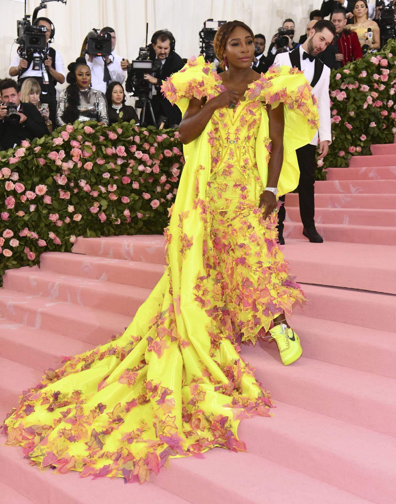 Serena Williams, quien será una de las presentadoras del evento junto a Lady Gaga y Harry Styles, camina por la alfombra rosa con un vestido amarillo neón de Versace.