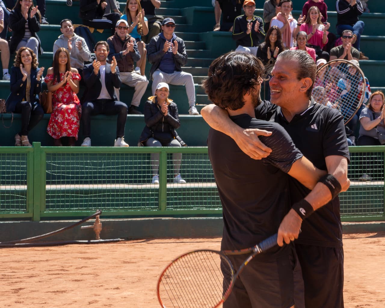 Abrazo entre Santiago (Diego Klein) y Don Alberto (Guillermo García Cantú) previo al partido de tenis.
