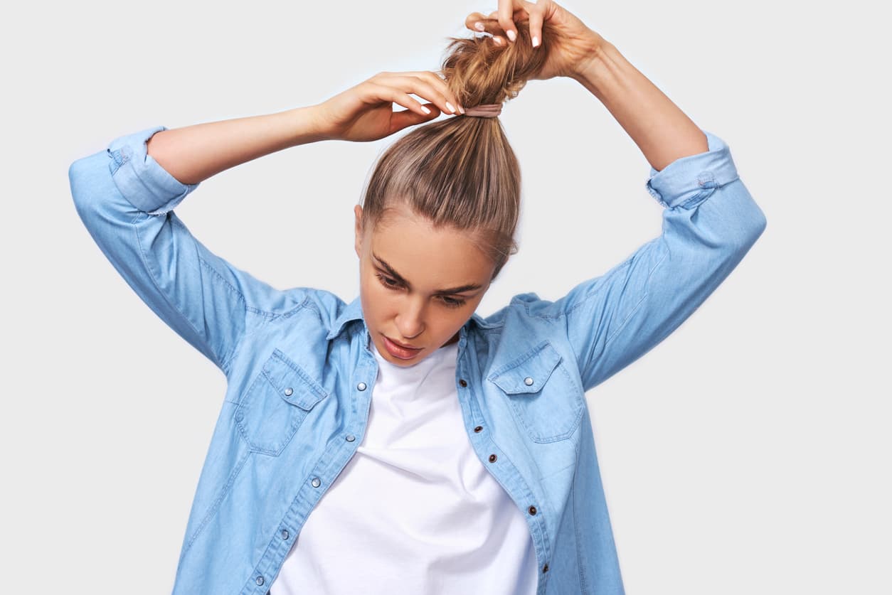 Joven mujer recogiendo el pelo en una cola de caballo