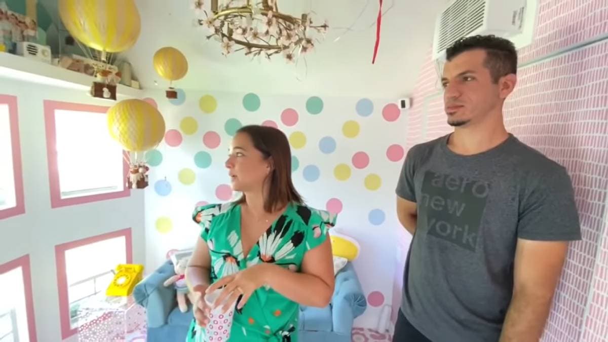 El sillón de la sala es de color azul y resalta con algunos cojínes de color blanco y amarillo; además al lado tiene una pequeña mesa con un télefono.