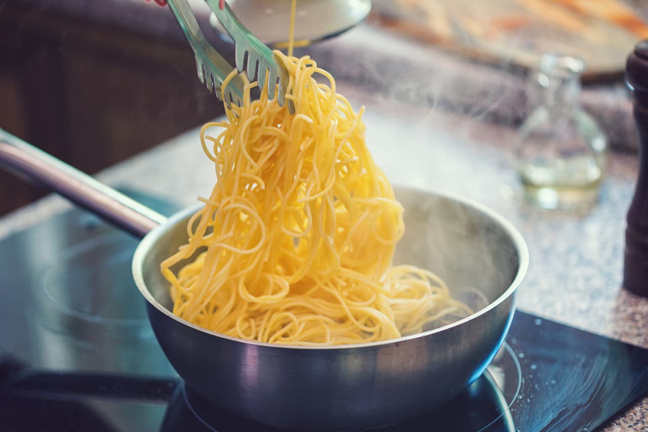 Young women preparing spaghetti alle Vongole at home