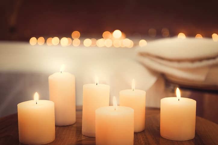 Close up of candles fire on small table. Bed for massage on background