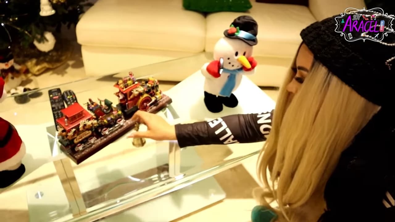 Al centro hay una mesa de cristal, sobre la cual colocaron muñecos de Santa Claus y de nieve que están tomándose selfies; además hay un tren navideño.