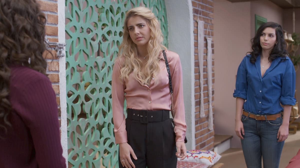 En esta imagen, Michelle Renaud luce una blusa de manga larga en rosa en una excelente combinación con pantalones negros de tiro alto.