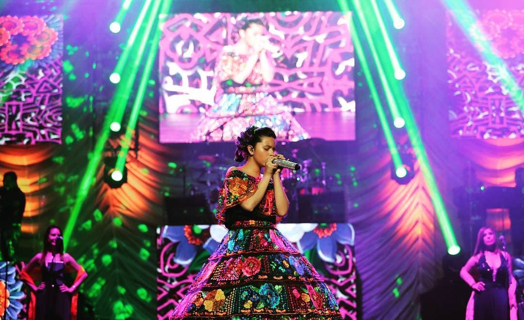 Los seguidores de Ángela saben que la joven toma en cuenta dos elementos para sus vestidos de gala: el corte princesa y detalles de folclore mexicano, por ello lució este diseño negro con flores de colores bordadas en febrero de 2017 en uno de los conciertos que realizó junto a su familia.