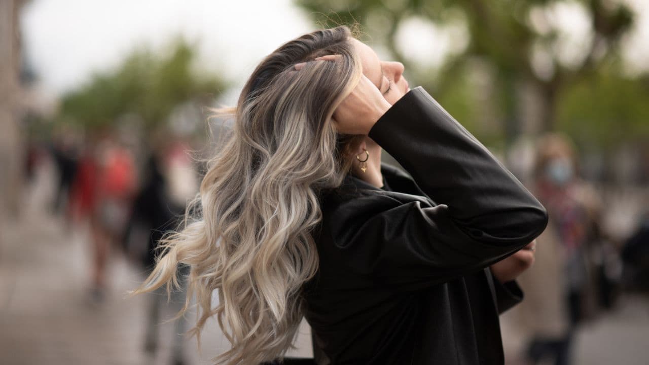 Joven en una ciudad tocándose el pelo blanqueado