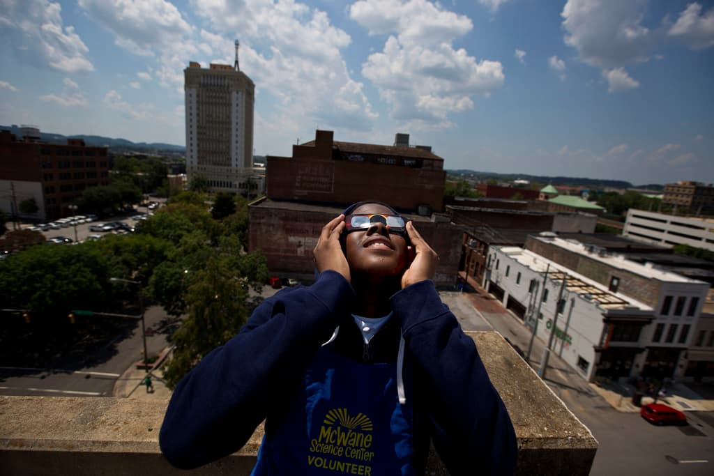 ARCHIVO - Justin Coleman, de Birmingham, Alabama, se pone las gafas en los ojos mientras observa el eclipse solar en lo alto de un aparcamiento, el lunes 21 de agosto de 2017, en Birmingham. Las gafas seguras para eclipses solares bloquean los rayos ultravioleta del sol y casi toda la luz visible. Cuando se usan en interiores, solo las luces muy brillantes deberían ser ligeramente visibles, no los muebles ni el papel pintado. (AP Photo/Brynn Anderson, Archivo)