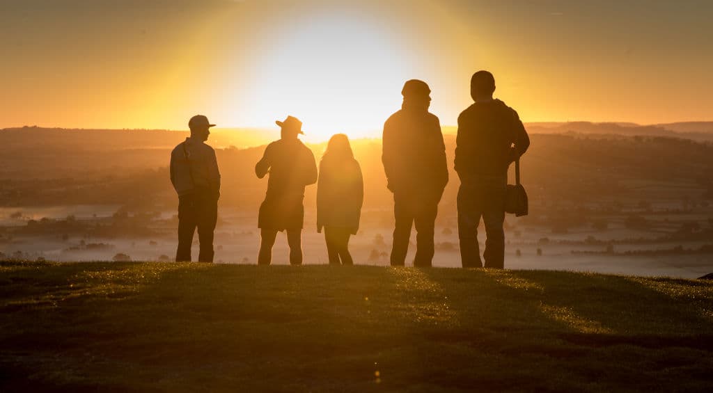 GLASTONBURY, ENGLAND - SEPTEMBER 22: People watch as the autumn sun rises over the Somerset Levels viewed from Glastonbury Tor near Glastonbury on September 22, 2017 in Somerset, England. Today marks the start of the astronomical autumn, which is defined by the Earth's axis and orbit around the sun. The transition from summer to autumn is defined by the autumn equinox, when day and night are of roughly equal length, but also signals that the nights will become increasingly longer than the days until the spring equinox, when the pattern is reversed. (Photo by Matt Cardy/Getty Images)