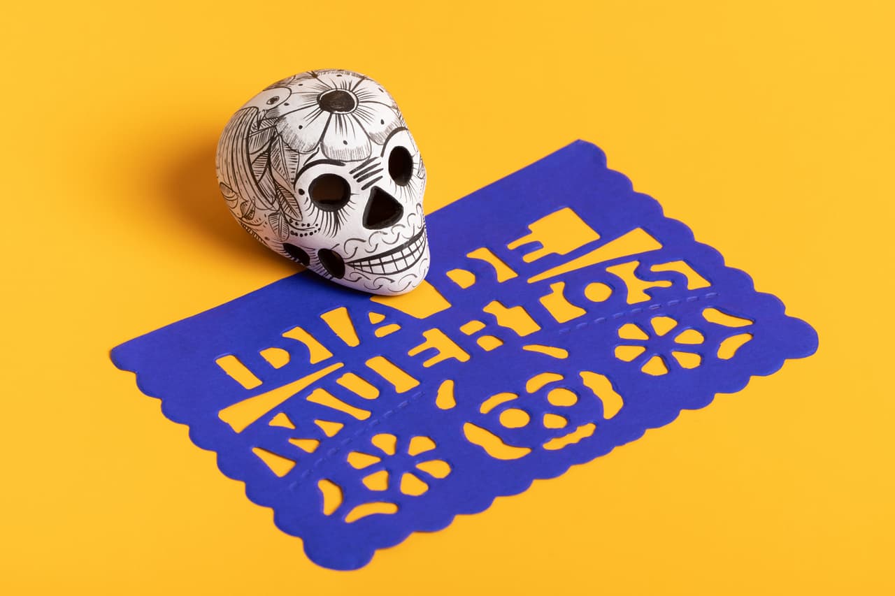 Day of the dead pottery skull (calavera) on blue papel picado on yellow background, Dia de Muertos background