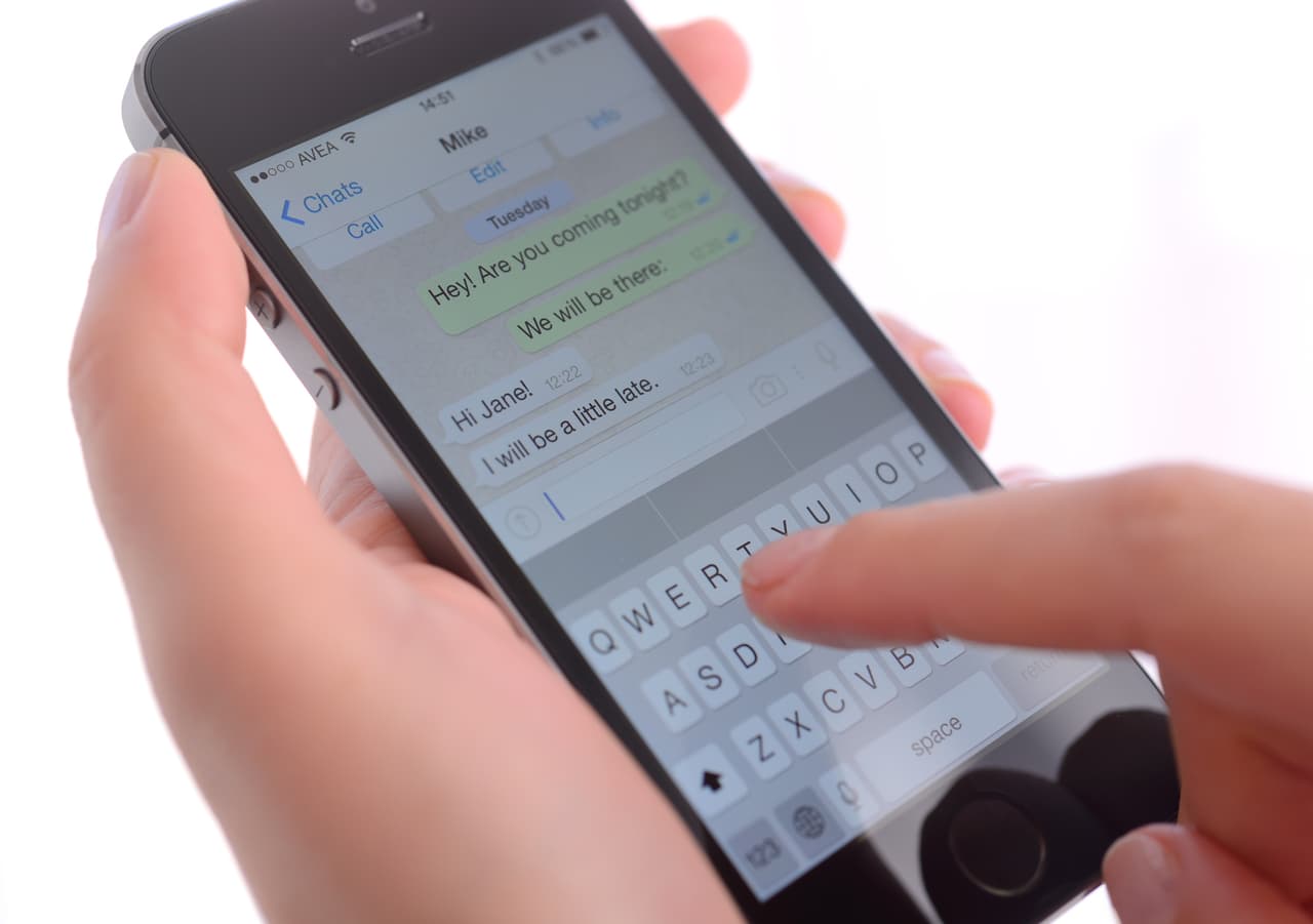 İstanbul, Turkey - January 24, 2015: Hand holding a iPhone 5s displaying Whatsapp application on a white background. iPhone is a touchscreen smart phone produced by Apple Inc.
