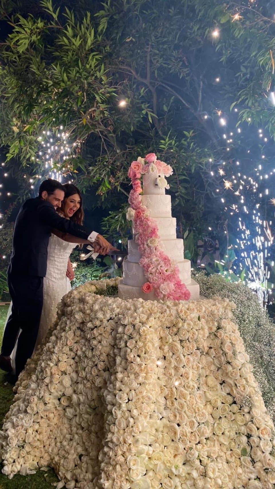 Una de las fotos más aplaudidas por los seguidores de la cantante es en la que aparece muy sonriente junto a su ahora esposo partiendo el pastel de seis pisos que dieron en la boda y que también estuvo decorado con flores rosas.