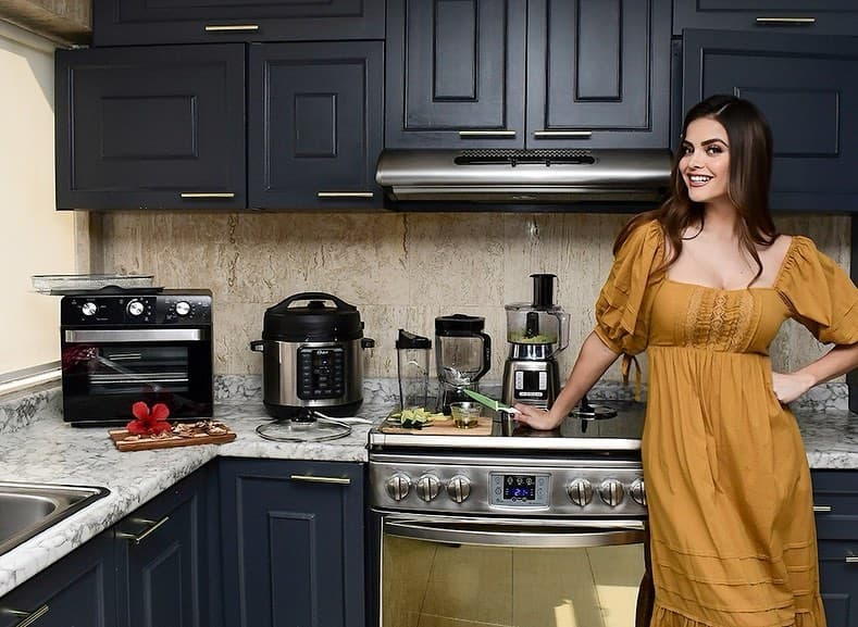 La cocina tiene gabinetes del mismo color que los sillones, combinando a la perfección con la cubierta de mármol y toda clase de electrodomésticos de acero inoxidable.